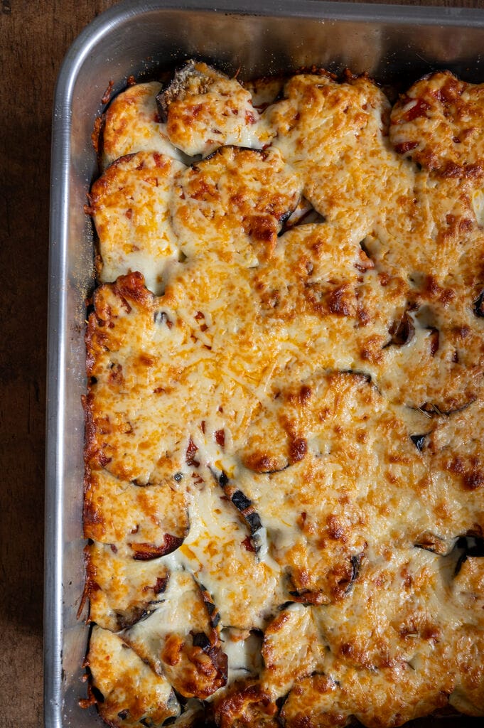 Eggplant, potato and mozzarella baked casserole in a stainless steel casserole dish.