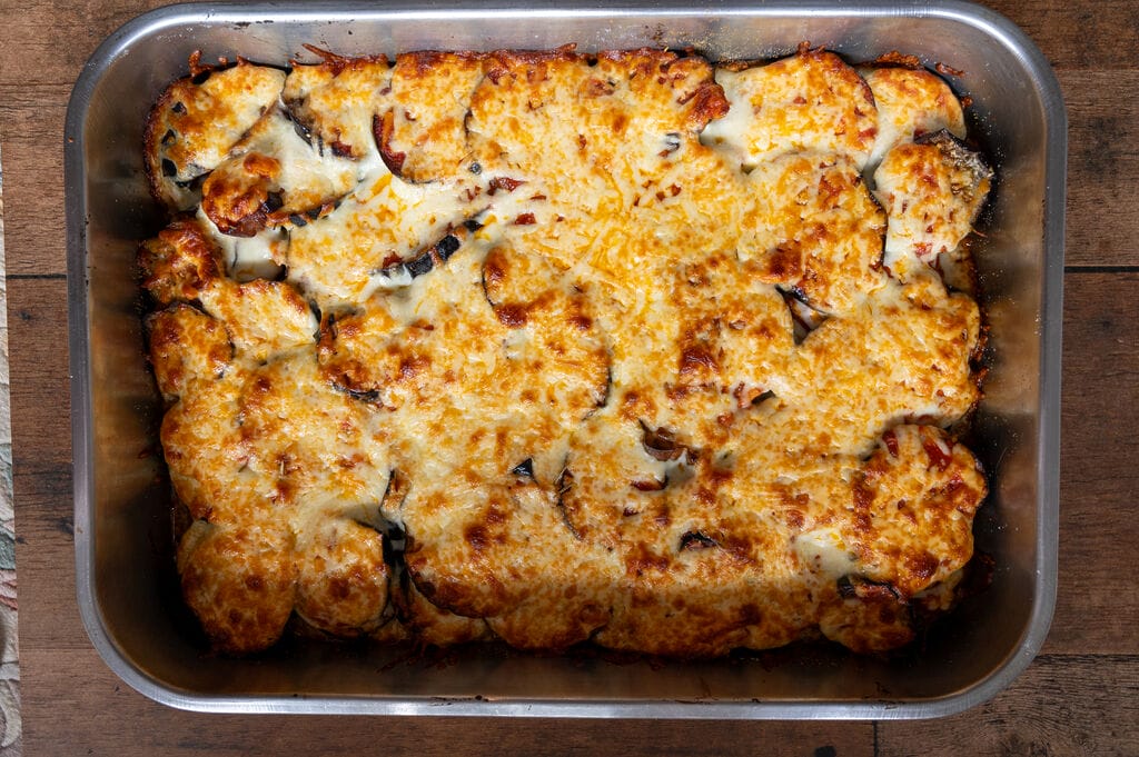 Eggplant, potato and mozzarella baked casserole in a stainless steel casserole dish.