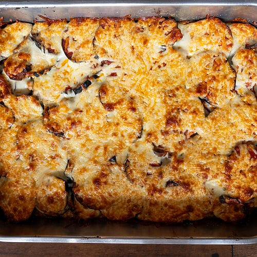 Eggplant, potato and mozzarella baked casserole in a stainless steel casserole dish.