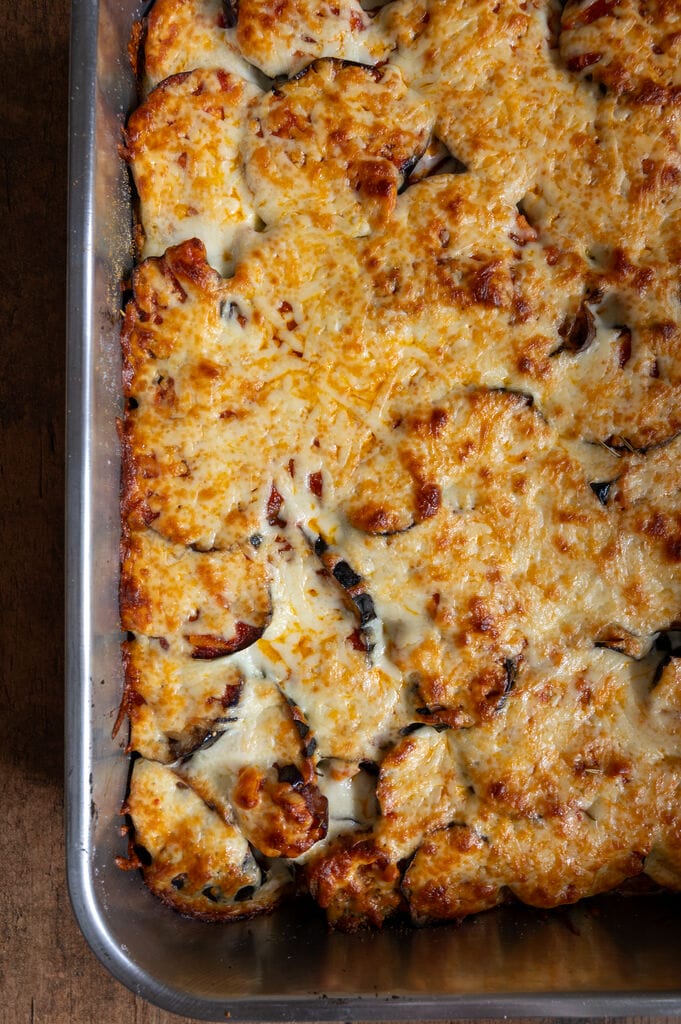 Eggplant, potato and mozzarella baked casserole in a stainless steel casserole dish.
