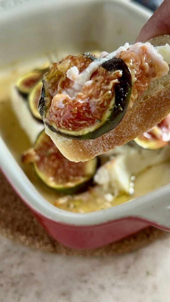 A piece of bread topped with baked Greek feta with figs.