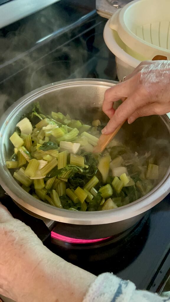 Adding the celery leaves and stems into the saucepot