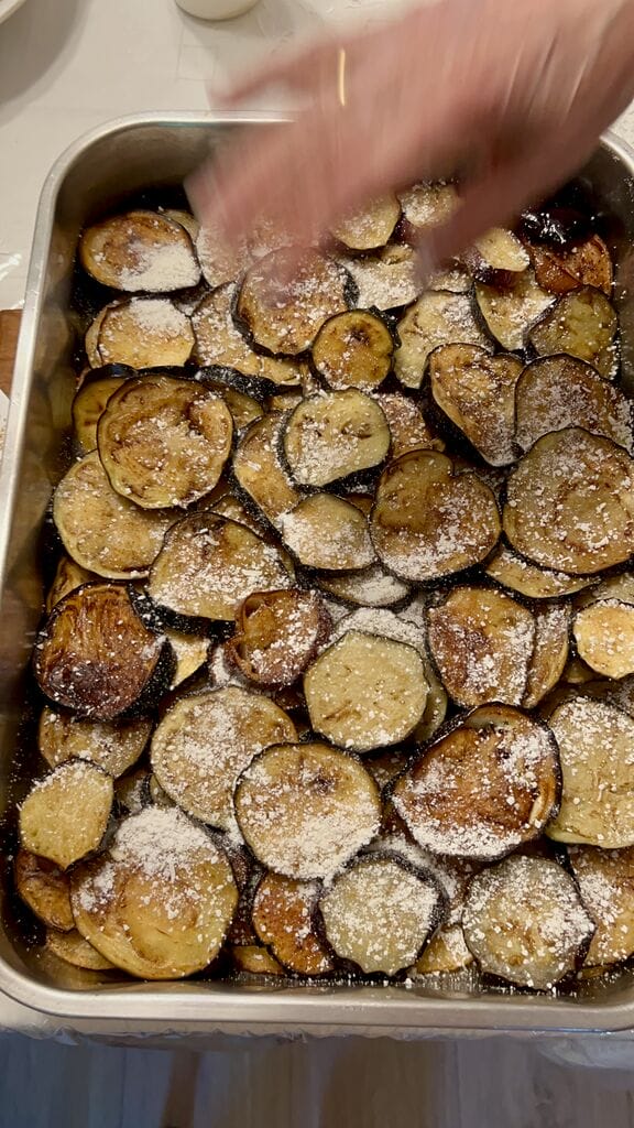 Sprinkling mizithra over the Eggplant, potato and mozzarella baked casserole.