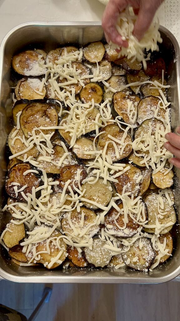 Sprinkling mozzarella over the Eggplant, potato and mozzarella baked casserole.