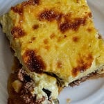 A piece of moussaka on a white plate.