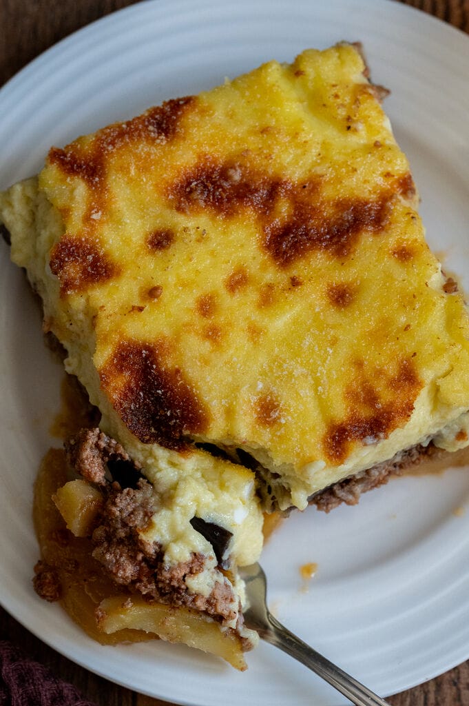 A piece of moussaka on a white plate.