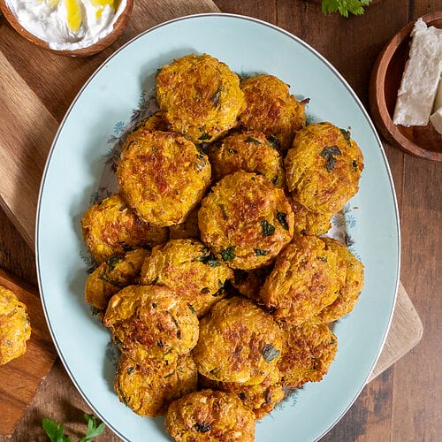 Baked squash fritters with feta on a white platter.