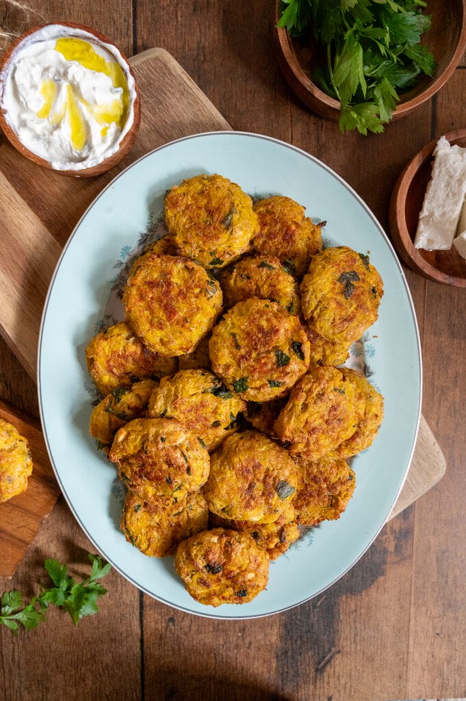 Baked squash fritters with feta on a white platter.