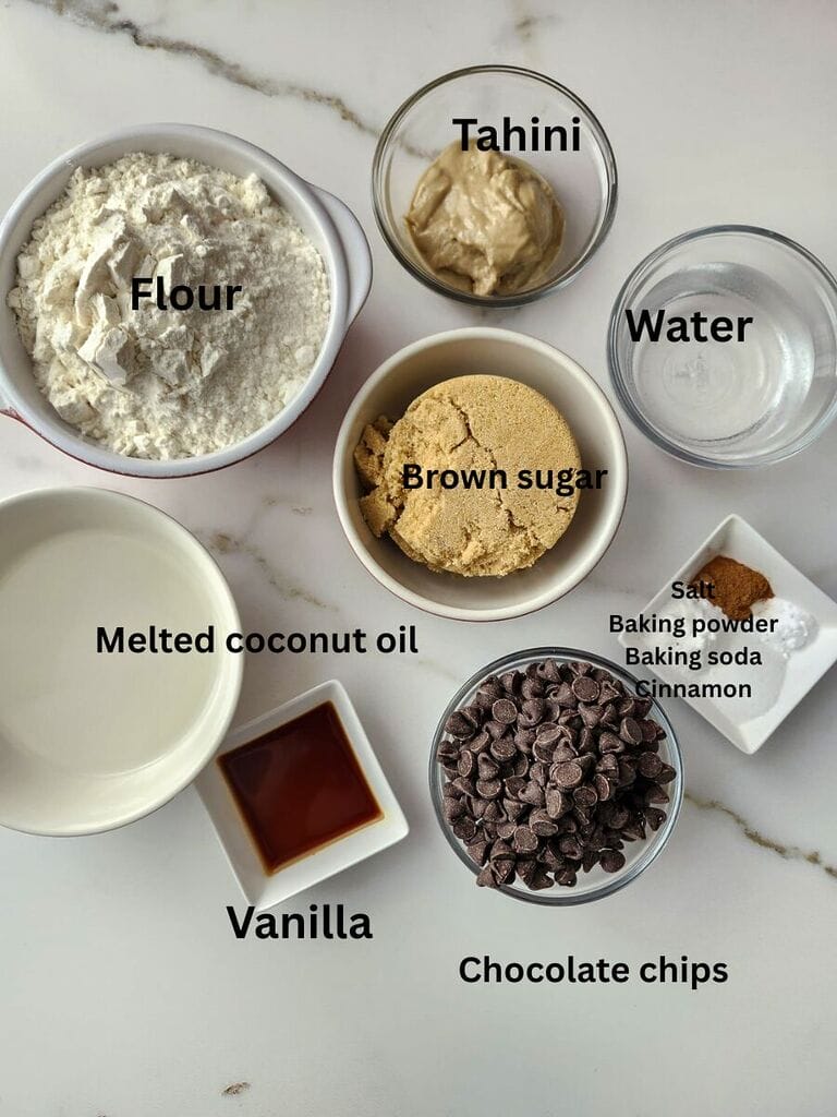 Ingredients which include: Flour, tahini, melted coconut oil, brown sugar, water, salt, baking powder, baking soda, cinnamon, vanilla and chocolate chips.