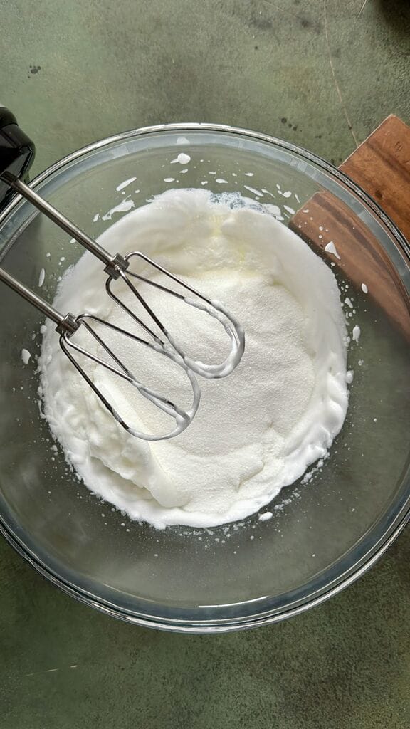 Combining the sugar to the egg white mixture.