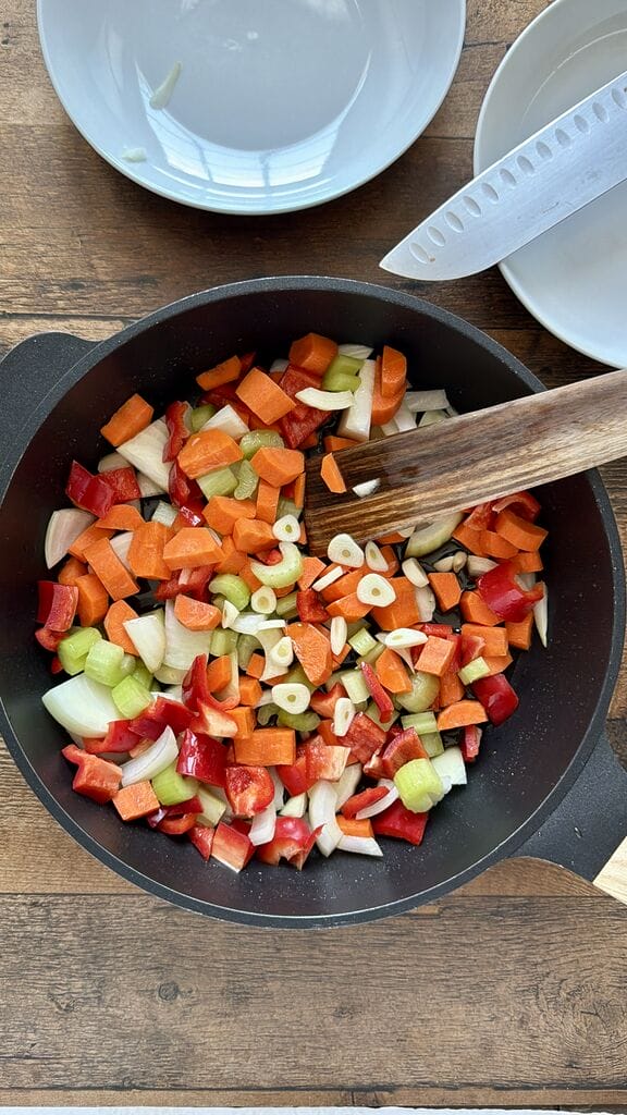 Caramelizing the veggies in a black frying pan.