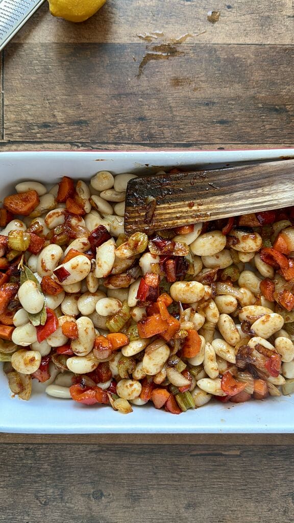 Greek Baked Gigantes with Sausage (Loukaniko), in a roasting pan ready to go in oven.