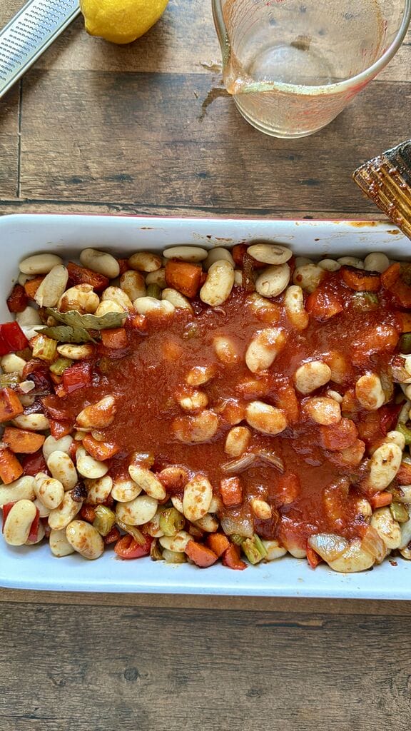 Greek Baked Gigantes with Sausage (Loukaniko), in a roasting pan ready to go in oven.