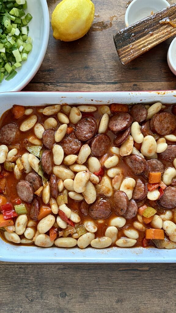 Greek Baked Gigantes with Sausage (Loukaniko), in a roasting pan ready to go in oven.