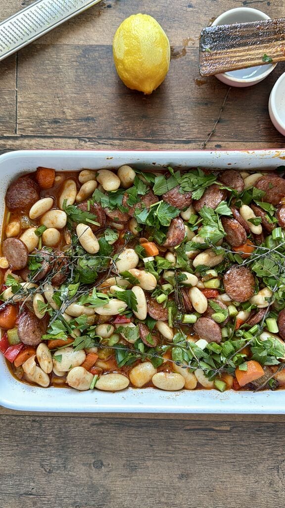 Greek Baked Gigantes with Sausage (Loukaniko), in a roasting pan ready to go in oven.