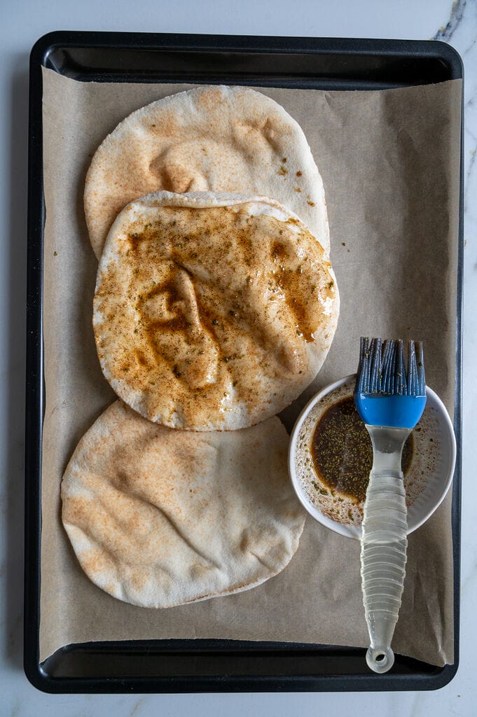 Basting the pita bread with the olive oil mixture.