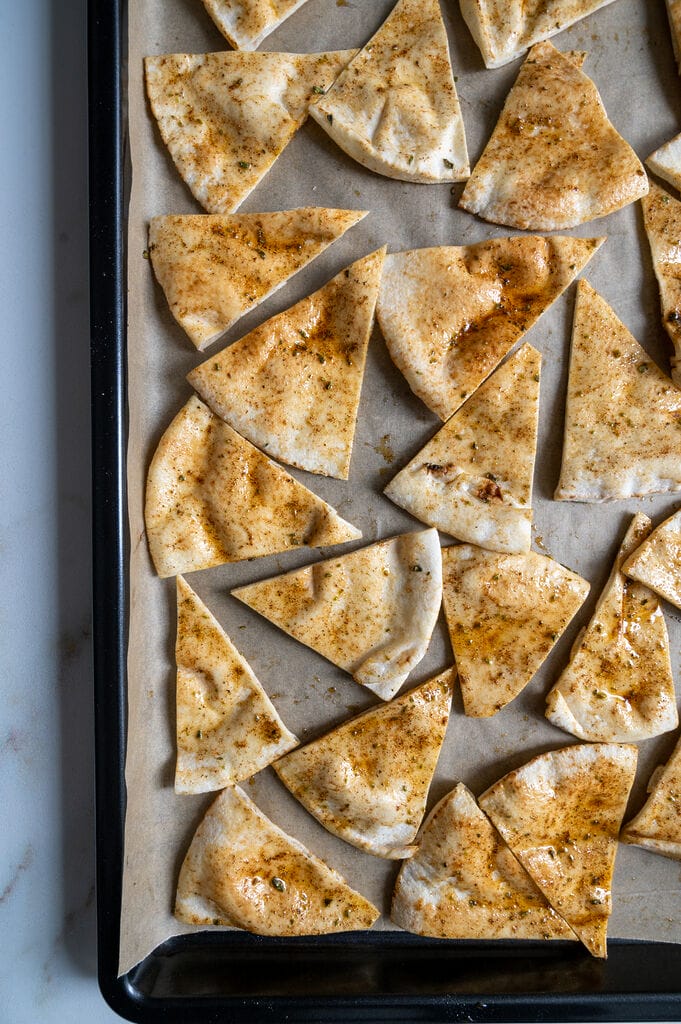 Pita bread cut up and seasoned and ready to bake.