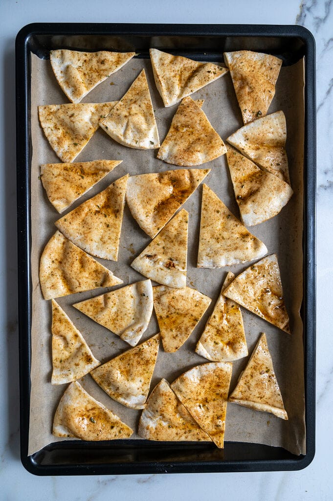 Pita bread cut up and seasoned and ready to bake.