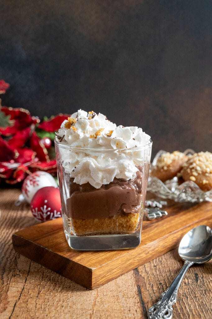 Greek melomakarona chocolate pudding in a glass tumbler, topped with whipped cream.