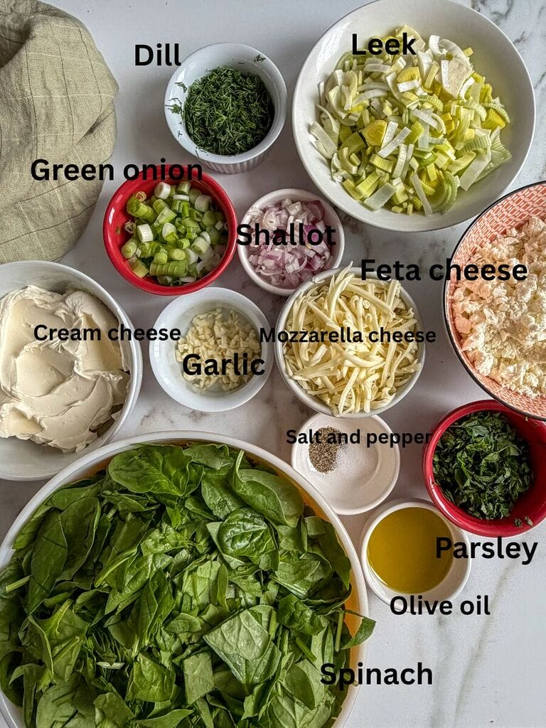 Ingredients which include: spinach, cream cheese, feta cheese, mozzarella cheese, green onions, dill, parsley, shallot, salt, pepper, olive oil, leek.