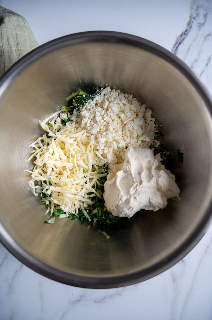 Combining the sautéed spinach with the 3 cheeses: Mozzarella, feta cheese, and cream cheese.