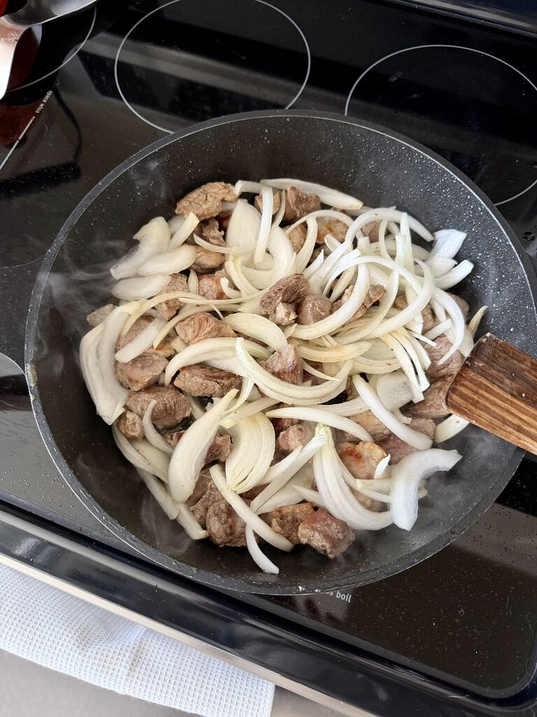 Adding the onion to frying pan.