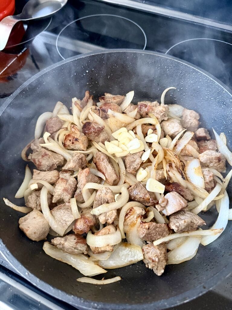 Frying the pork, onion and garlic.