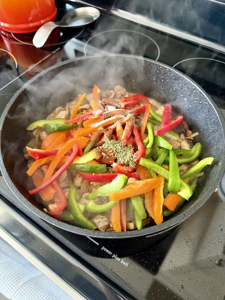 Adding the peppers and spices to frying pan.