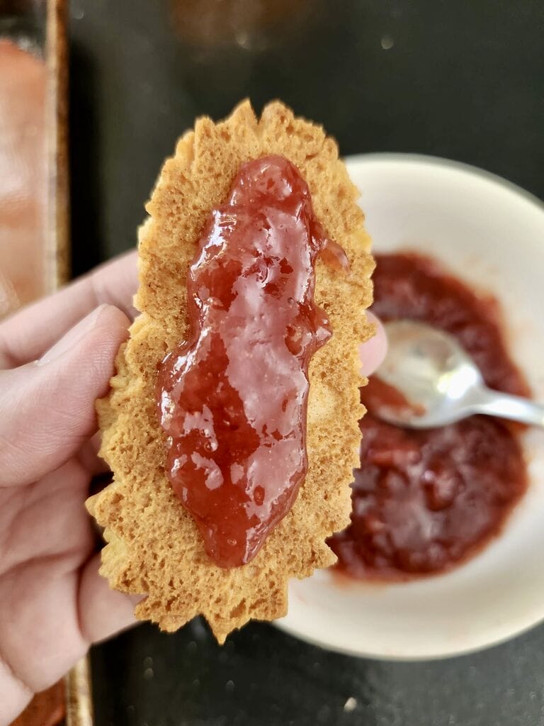 Spreading jam on the cookie.