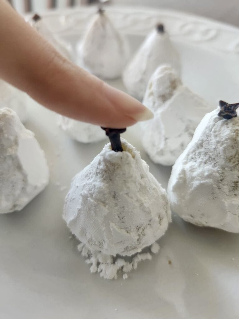 Pushing the clove into the cookie.