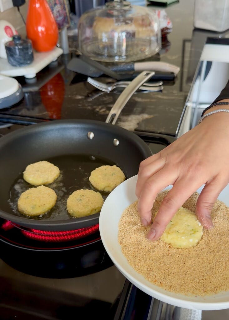 Coating the fritter in breadcrumbs before frying.