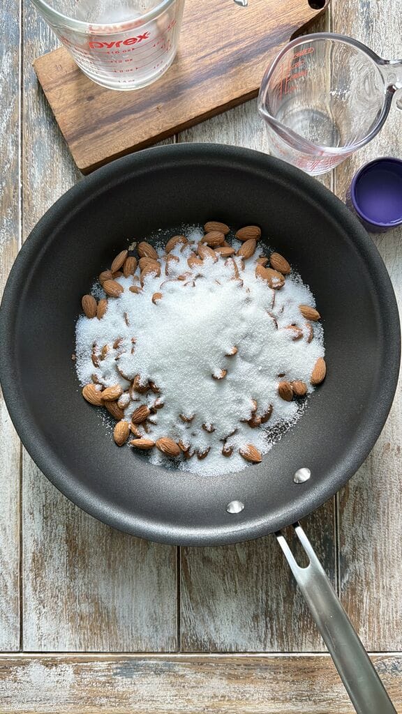 Adding the sugar to the almonds in the frying pan.