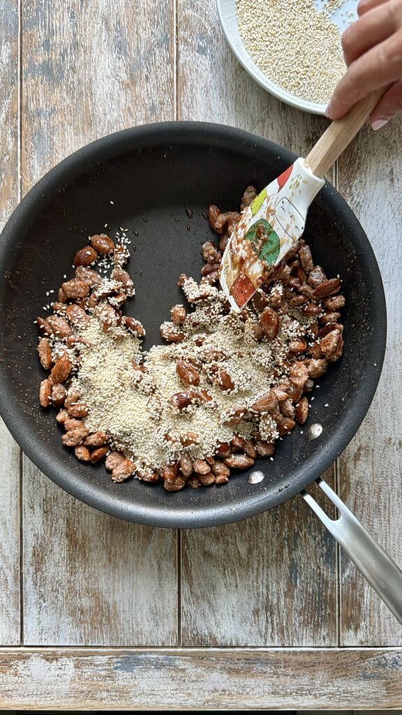Adding the sesame seeds to the caramelized almonds.