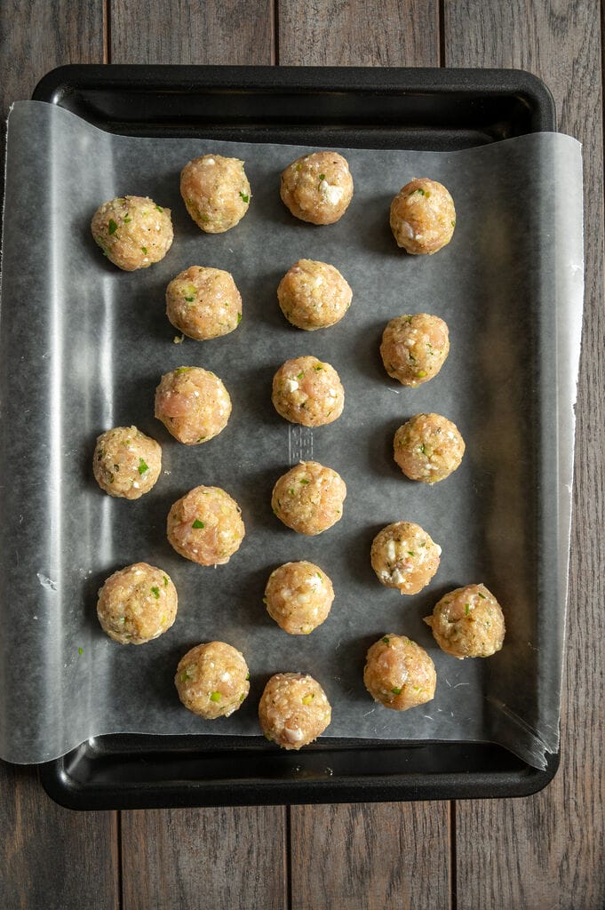 The shaped meatballs sitting on a tray waiting to be fried.