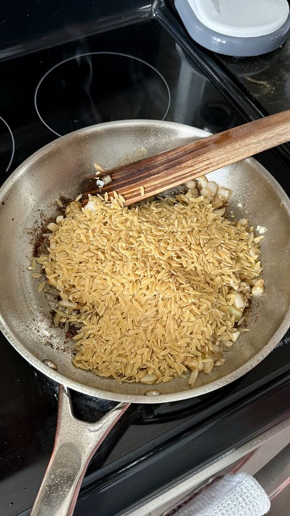 Adding the orzo to the frying pan.