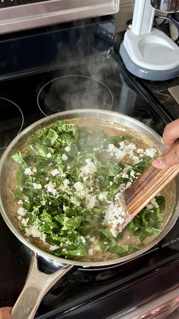 Adding the swiss chard and feta to the frying pan.