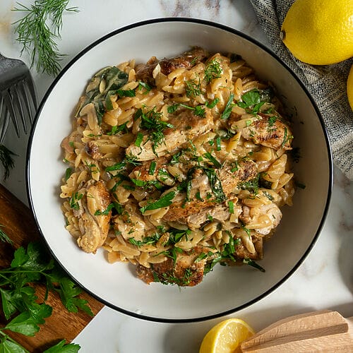 Creamy Lemon Chicken Orzo Recipe with Swiss Chard and Feta in a white bowl.