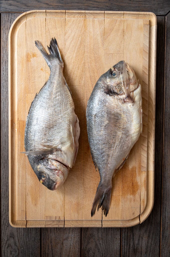 The 2 sea bream fish on a wooden board.